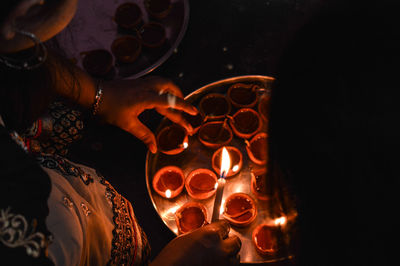 Midsection of person holding illuminated candles