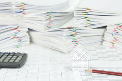 Close-up of model house with pencil and calculator on financial documents