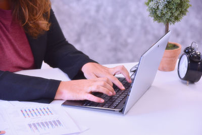 Midsection of person using mobile phone while sitting on table