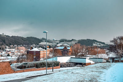 Buildings in snow covered city against sky 