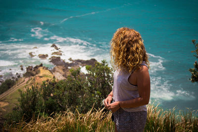 High angle view of woman standing on cliff against sea