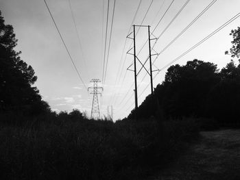 Low angle view of silhouette electricity pylon on field against sky