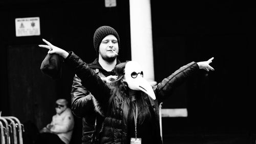 Young woman with arms raised standing at music concert