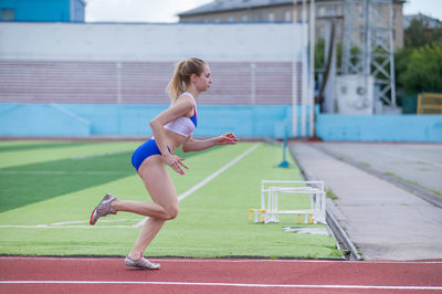 Full length of young woman exercising on court