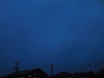 Low angle view of silhouette roof against blue sky