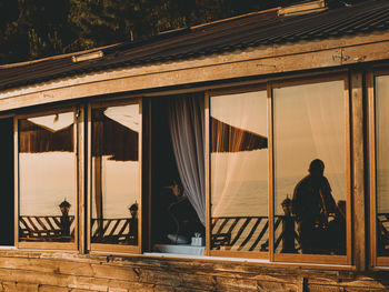 Rear view of man standing by window