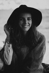 Portrait of young woman wearing hat sitting outdoors