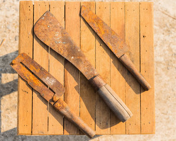 Directly above shot of rusty metallic knives on wooden table