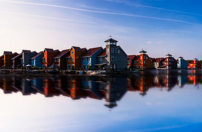 Symmetry view of buildings by sea against sky