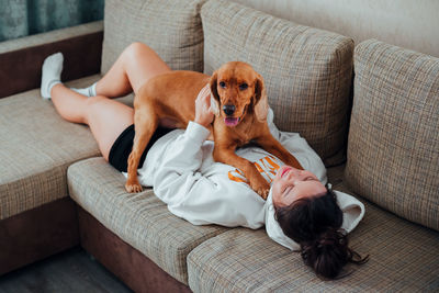 High angle view of woman with dog lying down on sofa at home