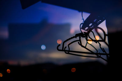 Close-up of illuminated lighting equipment against sky at sunset