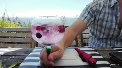 Close-up of hand holding glass of water on table