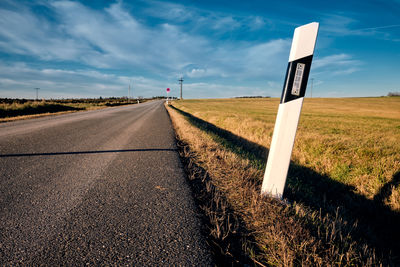 Empty road on field against sky