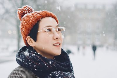 Woman looking away in city during snowfall