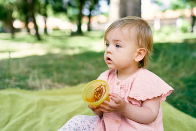 Cute girl with food sitting outdoors