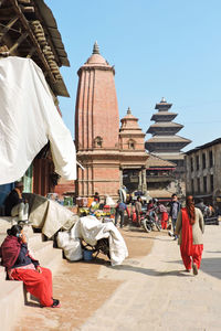 People outside temple against buildings in city