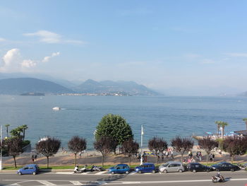 Cars on road by sea against sky