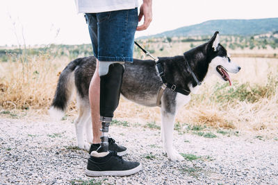 Young man wearing leg prosthesis with dog on dirt track