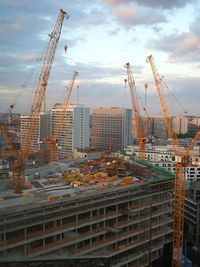 Cranes at construction site against buildings in city
