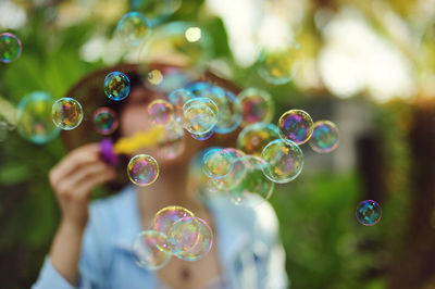 Woman blowing bubbles while standing at park