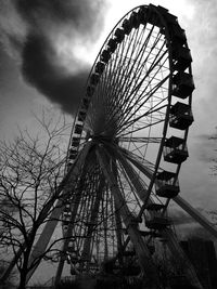 Low angle view of ferris wheel against cloudy sky