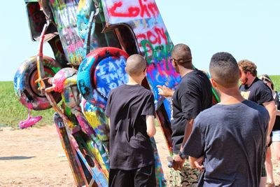 Men standing by graffiti car on sunny day