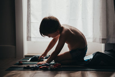 Side view of shirtless boy sitting at home