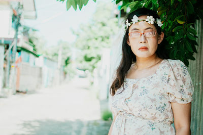 Young woman looking away while standing against plants