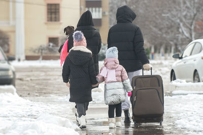 Rear view of people walking on snow