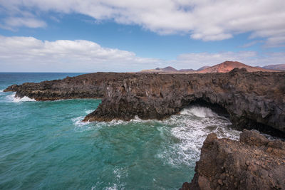 Rock formation in sea against sky