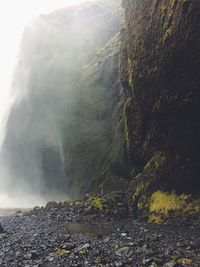 Person standing against cliff at skogafoss