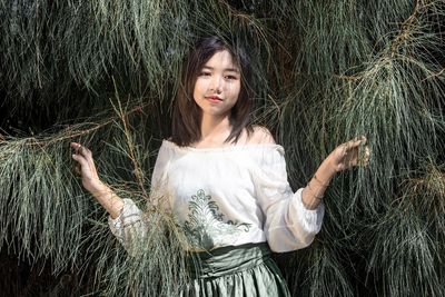 A beautiful girl standing among pine leaves in a pine forest and the dull sunlight.