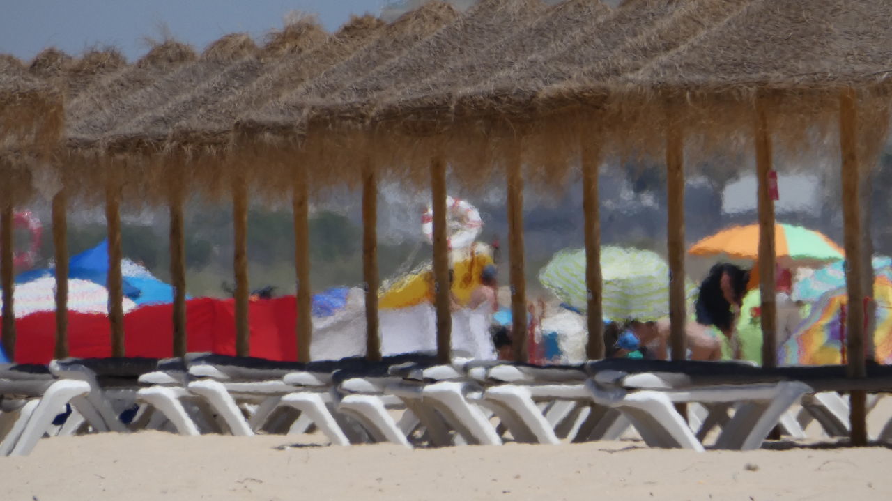 PANORAMIC VIEW OF PEOPLE ON BEACH AGAINST THE SKY