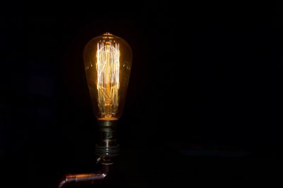 Close-up of illuminated light bulb against black background