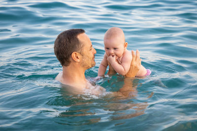 Father and daughter in sea against sky