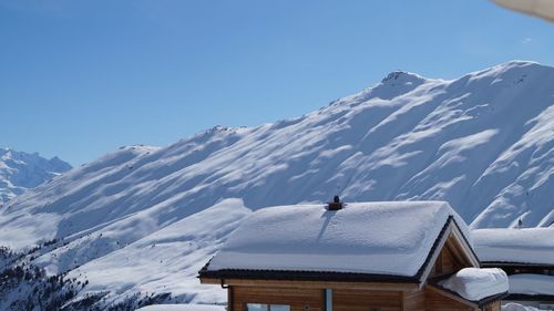 Snow covered buildings and mountains against sky