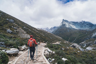 Rear view of man standing on mountain against sky