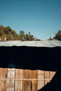 Fence by house against clear blue sky