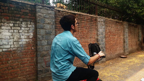 Man riding bicycle against brick wall