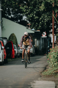 Rear view of man riding bicycle on road