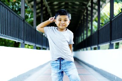 Portrait of smiling boy standing on footbridge