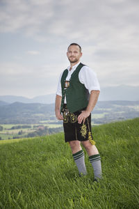 Portrait of man standing on field against sky