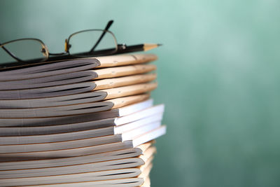 Stack of books with pencil and eyeglasses at classroom against blackboard
