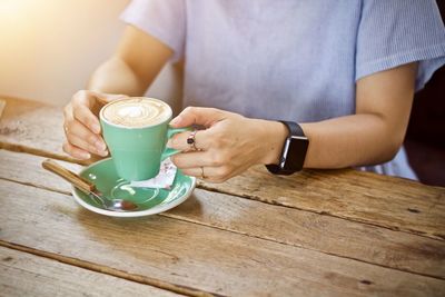 Midsection of man holding coffee cup on table