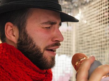 Close-up of man wearing scarf and hat singing song 