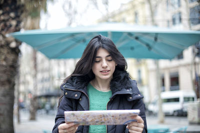 Young woman looking at camera while standing in city