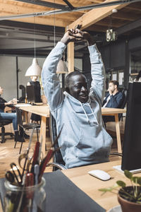 Smiling computer programmer stretching at workplace