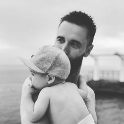 Portrait of shirtless man with baby in water