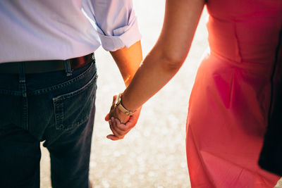Rear view of couple holding hands outdoors