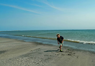 Full length of boy walking at beach against sky